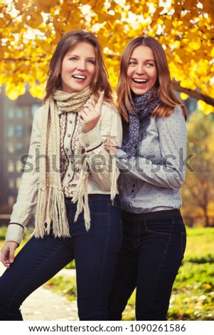 Two happy young fashion girls walking in city street Stylish teenage models wearing dark blue jeans and white shirts