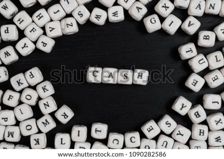 Word CASH on wooden cubes on a black wooden table with copy space