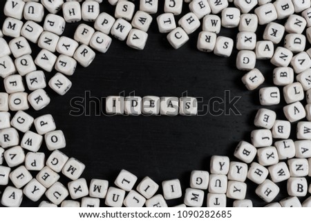 Word IDEAS on wooden cubes on a black wooden table with copy space