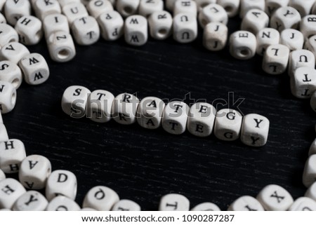 Word STRATEGY on wooden cubes on a black wooden table with copy space