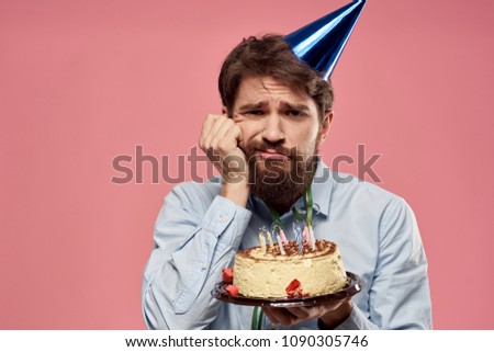 sad man in a blue cap and with a cake in his hand celebrate Birthday                           