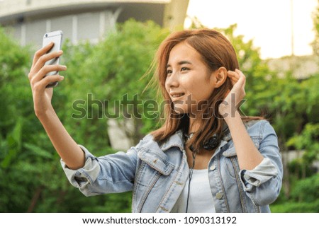 Young Asian woman taking a selfie with smartphone outdoor. Lifestyle and technology concept.
