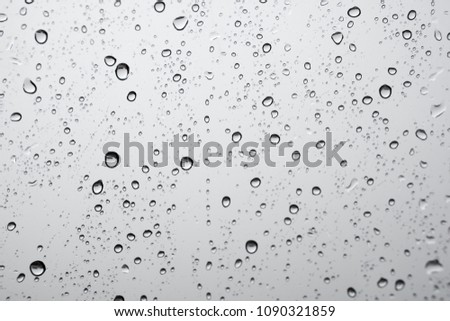 texture of rain drops on window glass over blur and cloudy sky background 