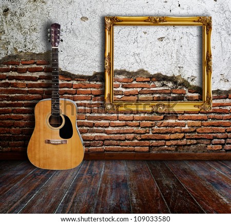 Guitar and picture frame in grunge room.