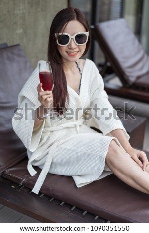 woman clothed bathrobe sitting on deckchair in swimming pool