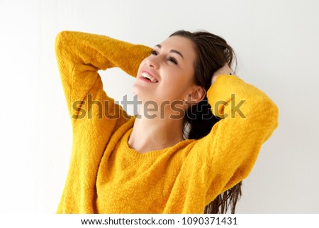 Close up portrait of smiling young woman with hands behind head and looking up