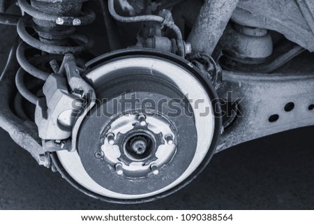 Close-up blue toned photo of shiny brake disk and suspension spring. Replacing wheel on modern SUV car