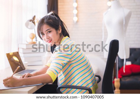 Happy young Asian woman fashion designer working in the studio