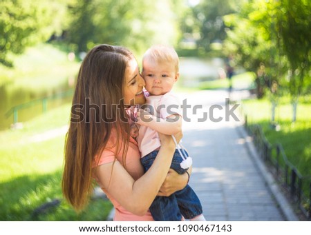 Youmg happy woman playing with her cute baby in summer sunny park outdoor. Mothercare picture