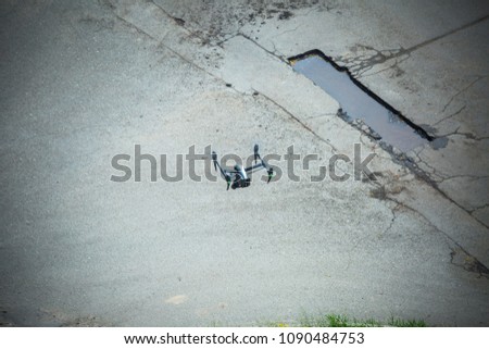 Quadcopter UAV`s drone for commercial aerial photography flying over old asphalt road examines exploring the defects of the road surface.