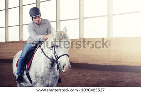 Young people on a horse training in a wooden arena

