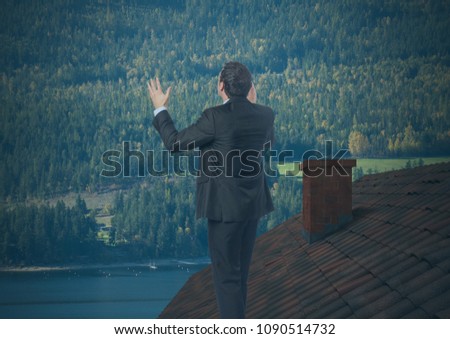 Businessman standing on Roof with chimney and forest mountain