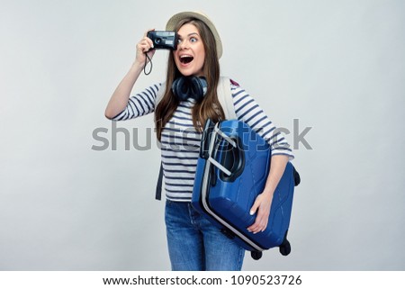 Surprised woman tourist taking pictures with camera. Girl traveler holding suitcase. Young modern woman.