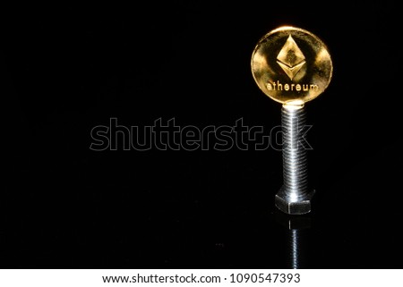 A large hex head bolt supporting a Etherum ether one ounce gold coin on the right side of image leaving room for text. 