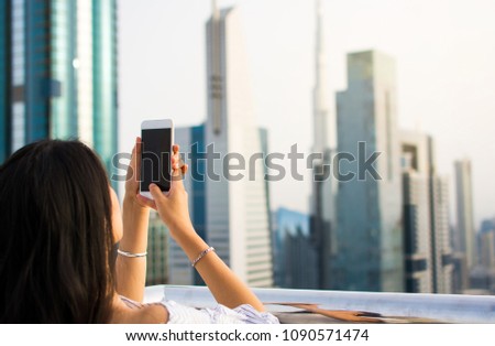 Girl taking picture of Dubai cityscape by phone