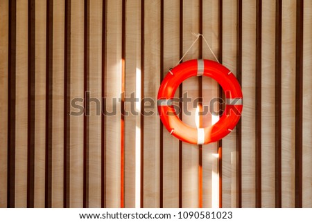 Red lifebuoy hanging on blue wooden wall of a port building