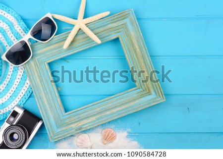 Beach travel concept mock up with frame and surrounding accessories on a blue wood background. Flat lay with copy space.
