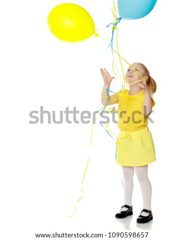 A lovely little round-faced blonde girl, with very long beautiful hair, in short skirts and yellow jerseys.She holds balloons in her hand.Isolated on white background.