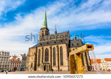 St. Bartholomew's Cathedral in the main square of Plzen with a fountain on the foreground against blue sky and clouds sunny day. Czech Republic, Pilsen. Famous landmark in Czech Republic, Bohemia. Royalty-Free Stock Photo #1090607273