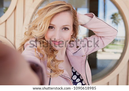 Portrait of beautiful retro woman against glass circle taking selfies photos, smiling networking outdoors. Vintage female using technology, hand holding camera lense, recreation leisure lifestyle.