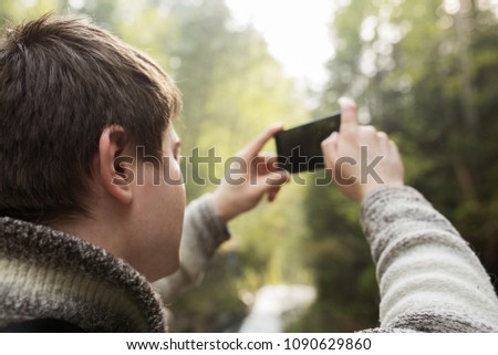 Male tourist taking image in the forest of the Carpathians on his smartphone