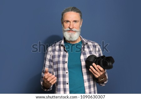 Male photographer with professional camera on color background