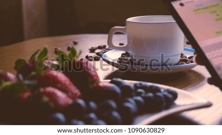 A cup of coffee and coffee beans, blueberries and strawberries, correspondence by SMS	