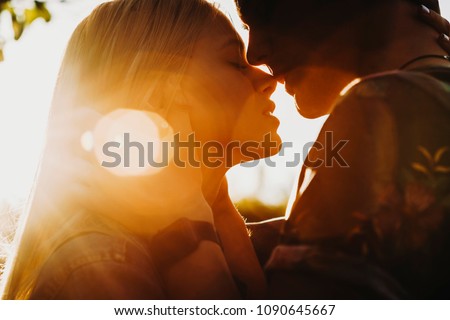 Close up portrait of a beautiful young couple waiting to kiss in their traveling time against sunset light. Royalty-Free Stock Photo #1090645667