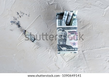 Package of cigarette filled with paper money dollars banknote instead of sticks and Cigarette butt. Smoking is bad for your health, actually burning / wasting money .World No Tobacco Day. Top view.