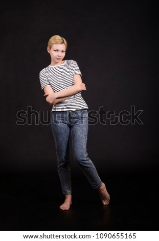 Young woman in striped t-shirt posing emotionally on dark background. Isolated image, Studio shot on dark background.