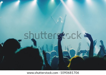Singer applauding to the crowd of people at music concert with raised up hands