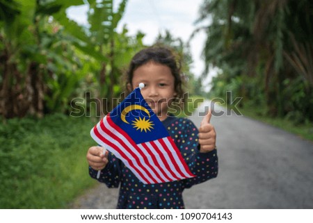 Portrait of young joyful girl with Malaysia flag. Merdeka theme concept. Malaysia's Independence Day. Selective focus.