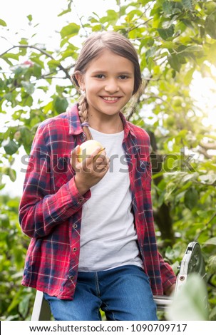 Beautiful smiling girl with appler posing in apple garden