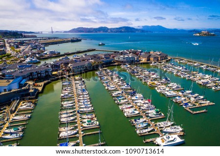 Aerial drone view above Bay Area Pier 39 and Docks , Sailboats , and yachts , with Alcatraz Island and San Francisco , California Golden Gate Bridge and entire Bay view Royalty-Free Stock Photo #1090713614