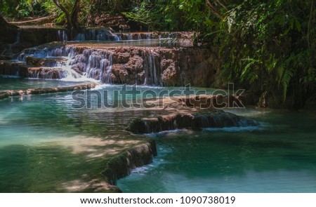 Focus on a beautiful waterfall with turquoise natural pools and vegetation around Royalty-Free Stock Photo #1090738019
