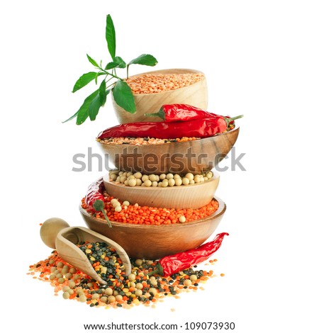 Different colorful lentils in a wooden bowl, soya beans, red chilli peppers with leaves