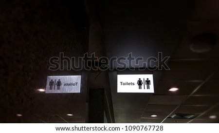 Toilet sign and reflection  on shiny wall in dark hall corner