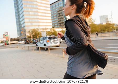 Back view photo of amazing young sports woman running outdoors on the street.