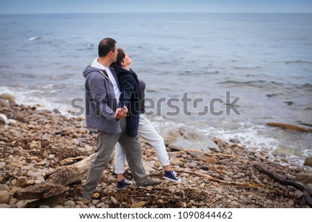 Beautiful couple on the beach at sunset. They are happy and wearing casual clothes