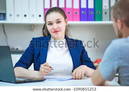 I am listening really carefully. Portrait of a brunette in the office taking a visitor at a table with a laptop. She sits right in front of the camera and talks to the client