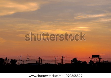 Sunset with large electric pole on the road at twilight time. Background is beautiful sky and cloud. Picture is silhouette style.