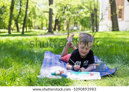 Cute little boy painting picture, outdoors