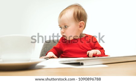 Happy child baby girl sitting with keyboard of modern computer or laptop isolated on a white studio background. early development of modern kids concept. Female caucasian up to a year old baby