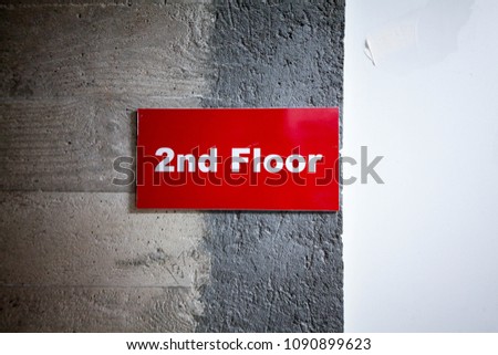 Red 2nd Floor sign with white letter on bare concrete and white wall background