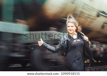 Nice girl in a black dress on a railway road near moving train
