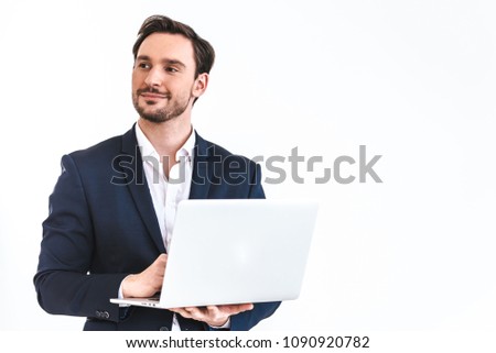 The happy businessman with a laptop standing on the white wall background