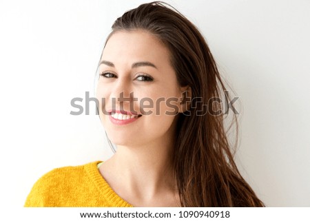Close up portrait of smiling young woman against white wall