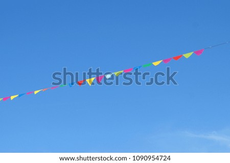 Festive colorful flags in the blue sky. Place for inscription / text.