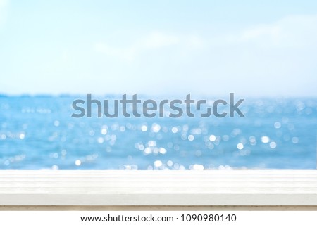 Empty plank white wood table top with blur blue sky and sea boekh background,summer holiday backdrop.Mock up template for display or montage of product or content use as panoramic banner in ads. Royalty-Free Stock Photo #1090980140