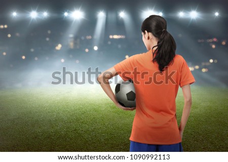 Young asian football player woman carrying the ball on the stadium